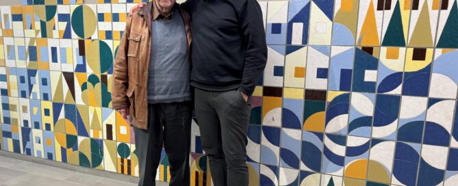 Zwei Personen stehen vor einer Mosaikwand