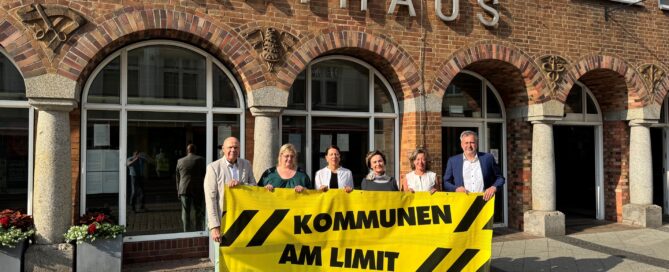 Vor dem Cottbuser Rathaus stehen Menschen und halten ein Plakat hoch