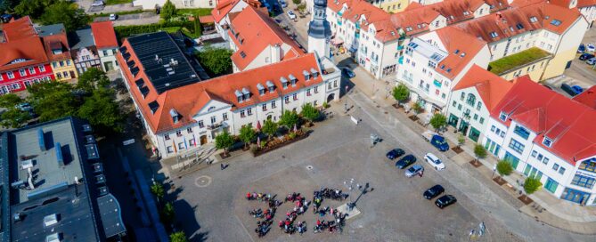 Das Drohnen-Foto zeigt Fahrradfahrer auf dem Marktplatz in Spremberg, die eine "725" bilden. Quelle: ASG Spremberg GmbH/chairlines