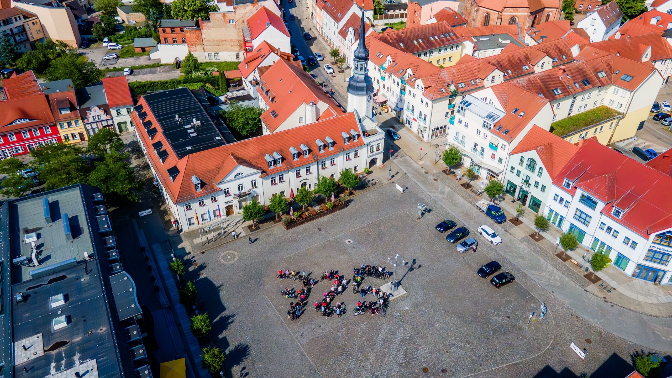 Das Drohnen-Foto zeigt Fahrradfahrer auf dem Marktplatz in Spremberg, die eine "725" bilden. Quelle: ASG Spremberg GmbH/chairlines