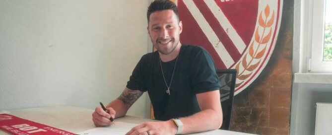 Ein Fussballspieler unterschreibt einen Vertrag