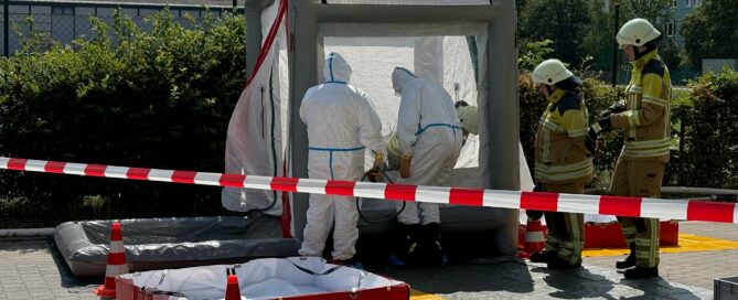 Einsatzkräfte sind in Schutzanzügen in einem Zelt