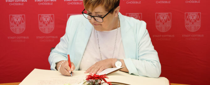 Eine Frau trägt sich in das Goldene Buch der Stadt Cottbus ein