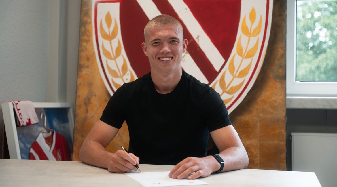 Ein Fussballspieler unterschreibt einen Vertrag