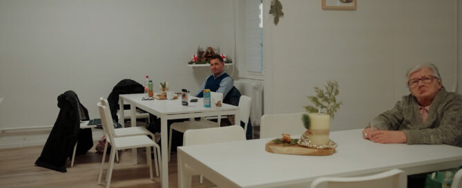Das Foto zeigt das Café der Stadtmission Cottbus von innen mit zwei Menschen an den Tischen.