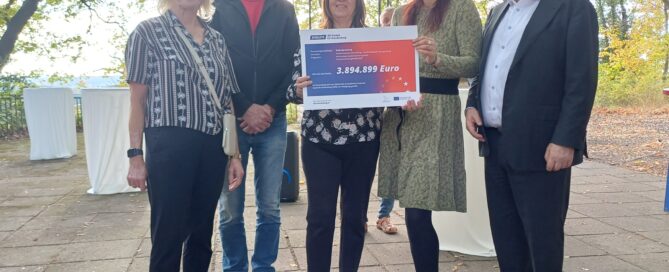 Menschen stehen mit einem Scheck nebeneinander